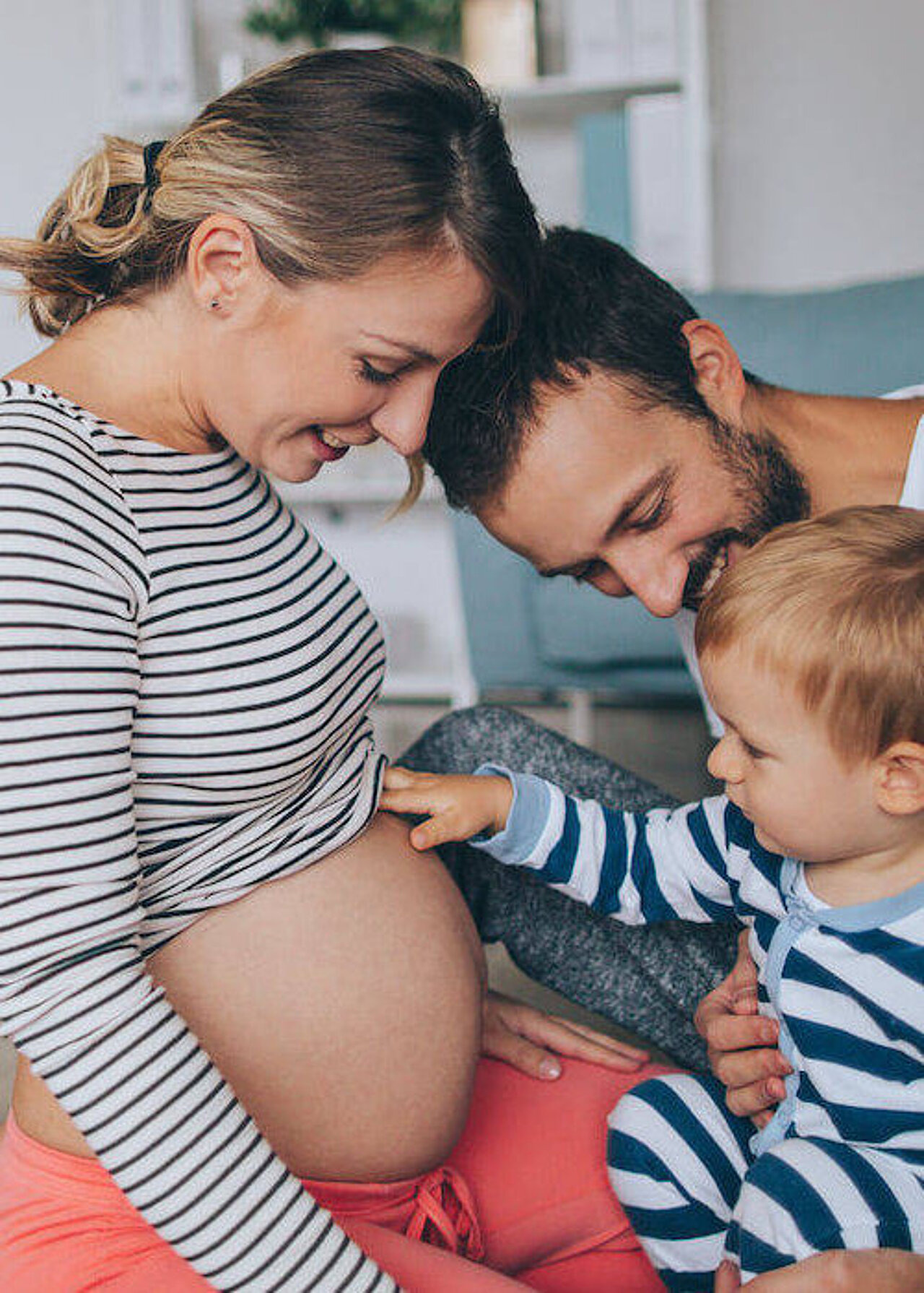 Eine Familie bestehend aus Vater, Mutter und Kind sitzt beisammen.