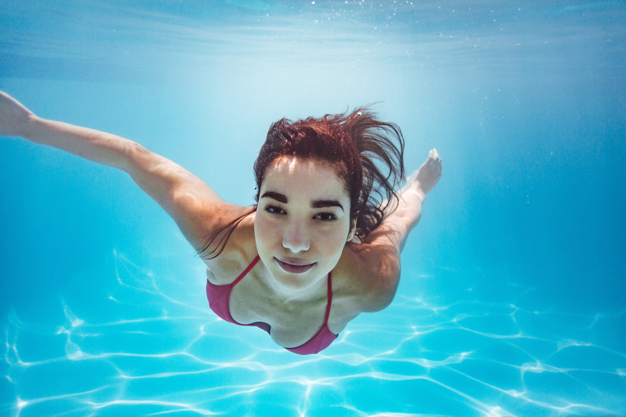 Mädchen schwimmt unter Wasser.